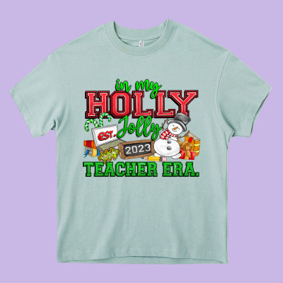 In My Holly Jolly Teacher Era Heavy Core Tee Designed By Cowhidedigitalart